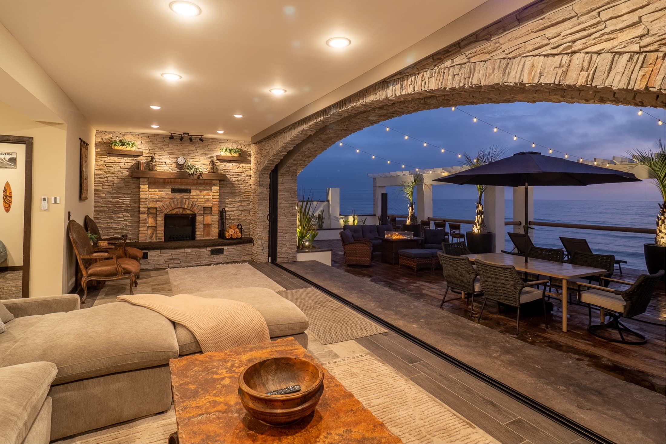 Living room with fireplace and stone arch opening to the deck