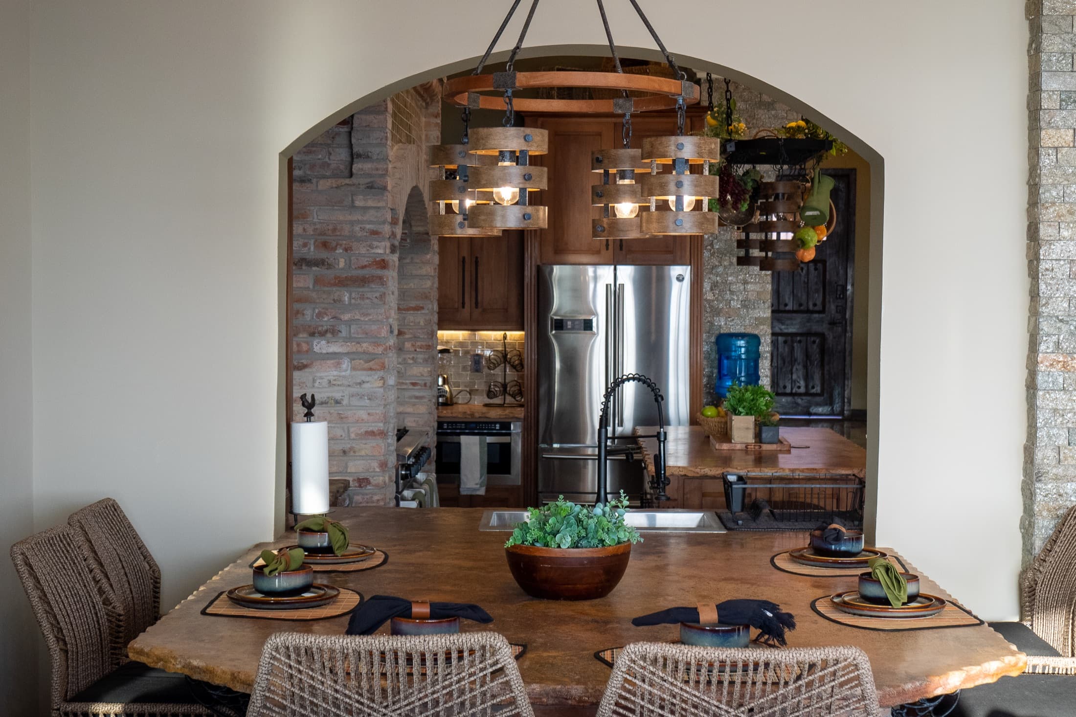 Dining area framed by a stone arch, kitchen beyond